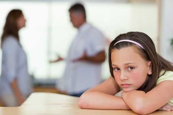 Sad girl with her fighting parents behind her