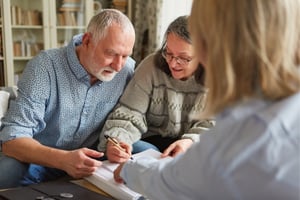 couple sitting with attorney signing estate planning documents